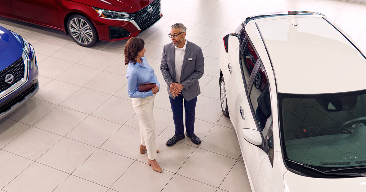 Customer and dealer in Nissan showroom by white car